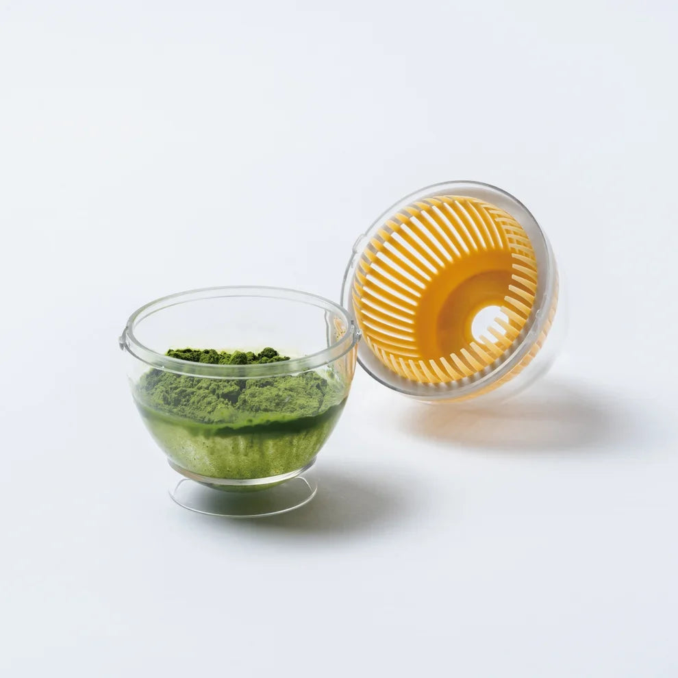 抹茶の粉と水を入れた透明な容器と、茶筅状パーツ付きのふた
