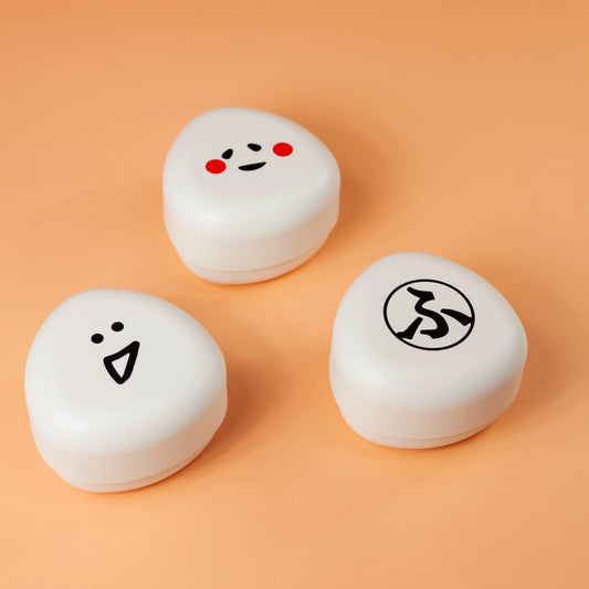 オレンジの背景に並べたfufufuおにぎりケース3柄 ふ、かお、おこめ