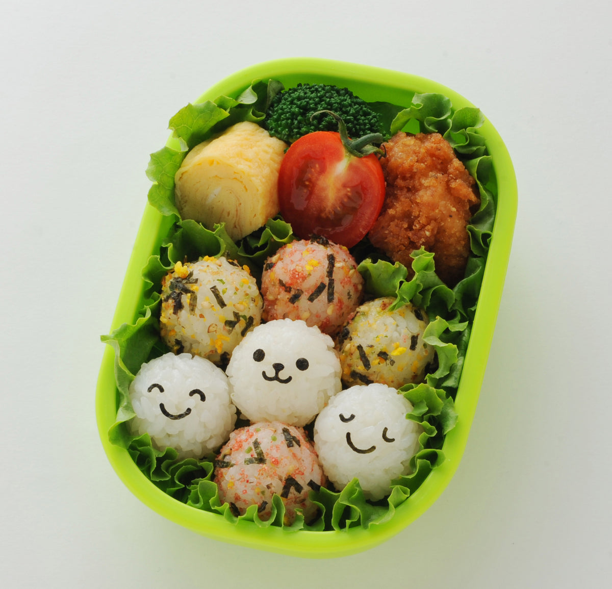 こむすびボール miniで作った顔付きミニおにぎり入りお弁当 — グリーンのお弁当箱に笑顔のおにぎりを詰めた例